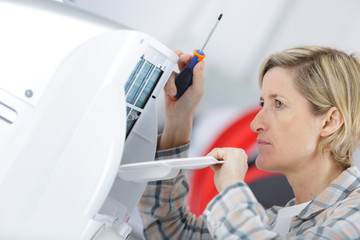 blonde handywoman cleaning fixing ventilation system