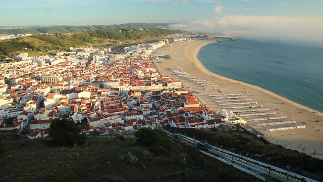 Moving trains of Railway Funicular in sunset skyline and beach waterfront from Miradouro do Suberco in Nazare Sitio, upper town above the giant cliffs in Central Portugal, Europe.