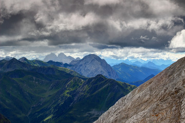 Rocky and grassy slopes of Carnic Alps main ridge from Kinigat with Kellerspitzen, Hohe Warte / Monte Coglians and Peralba peaks and Julian Alps in blue in background, Austria / Italy border, Europe
