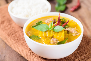 Thai food.Spicy pumpkin soup with pork and cooked rice in a bowl on brown fabric 