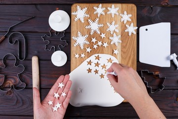 Process of cutting decorations in form of stars and snowflakes of confectionery mastic, view from above. Family culinary and New Year traditions concept, Christmas food