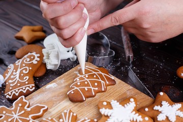 Christmas bakery. Decorating homemade gingerbread cookies with icing and confectionery mastic, close up. Festive culinary and New Year traditions concept