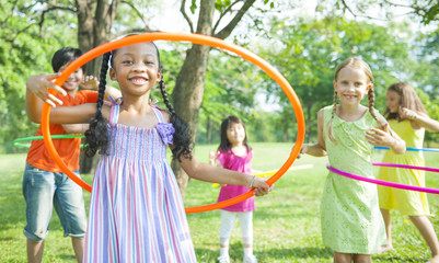 Cute diverse kids playing with hula hoops - Powered by Adobe