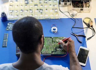 Technician using multimeter with computer electronics parts