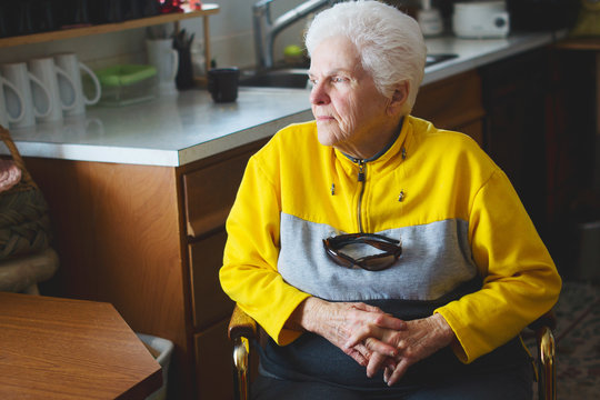 An older woman looks out her kitchen window
