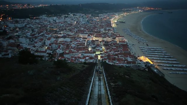Nazare, Portugal by evening, the most popular seaside resorts in Silver Coast. Prospective view of popular Ascensor da Nazare or Nazare Funicular from Nazare Sitio, the upper part of city. slow motion