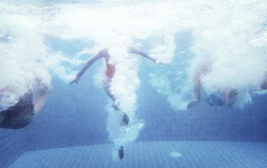 Fototapeta na wymiar An underwater shot of a group of people jumping down into a swimming pool