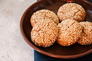 Homemade oatmeal cookies with sesame seeds in a plate on a white stone background