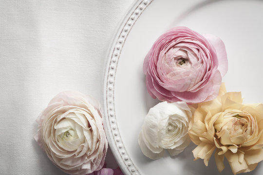 Table setting with plate and pastel colored ranunculus flowers