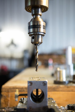 Industrial drill press on work table with metal shard remnants