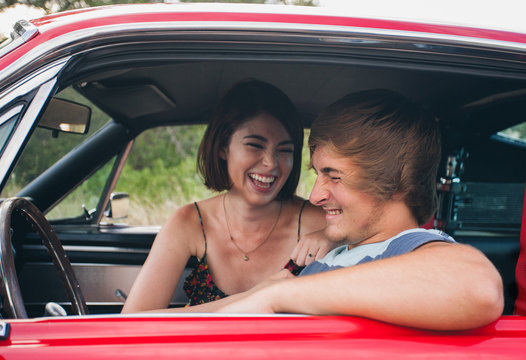 Playful young couple in classic car