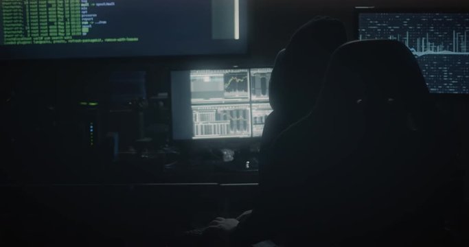 Cinematic shot of a hacker working at a console in a dark room.  Broadcast quality footage. 4K UHD.