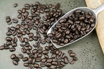 Close up of roast coffee beans in the scoop on the stone table background