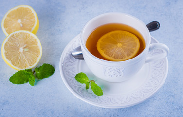 Cup of hot lemon tea with mint on blue stone table background. Healthy drink cold. Copy space. Winter drink