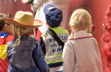 Young kids dressed up for preschool Halloween parade walking down school hallway