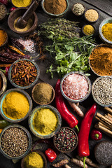 A selection of various colorful spices on a wooden table in bowls