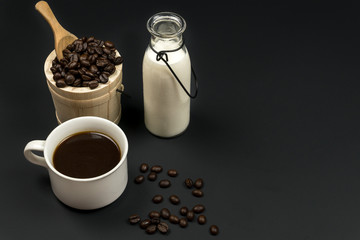 A cup of coffee and coffee bean grain on sack fabric put on black wood table background include copyspace for add text or graphic