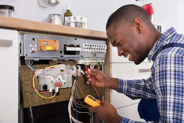 Technician Fixing Dishwasher With Digital Multimeter