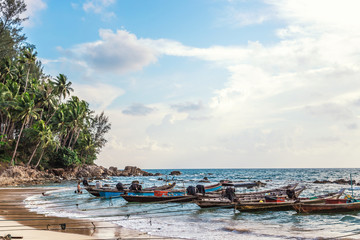 Sandy beach with colorful fishing boats at sunset. Phuket Thailand