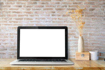 Mockup of laptop with empty screen and stationery items on light table in workspace interior.