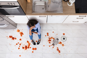 Woman Sitting On Kitchen Floor With Spilled Food