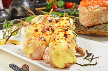 Chicken skewer with cheese on white plate