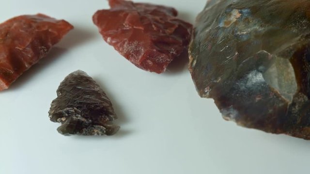 Close up group native American artifacts hand axe ax red obsidian arrowhead jasper chert Paiute Indian stone tool in dirt from Oregon great basin desert on white