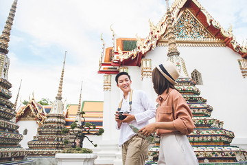 Obraz premium Young Asian photographer tourist with his girlfriend visiting Thai temple in Bangkok Thailand