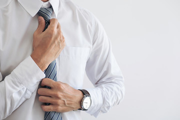 Close up of Young attractive businessman wears a gray tie and adjusting tie