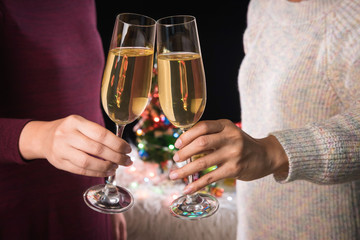 Beautiful two women holding glasses with champagne celebrating Christmas and gift boxes at corporate party and christmas lights, New Year Frame for your text