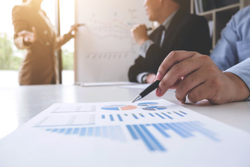 Business woman leader making presentation with her colleagues, pointing to the graph on board and business strategy during meeting in modern office