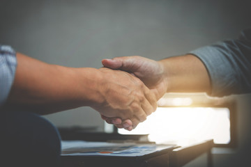 Obraz na płótnie Canvas Two business men shaking hands during a meeting to sign agreement and become a business partner, enterprises, companies, confident, success dealing, contract between their firms