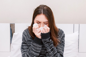 Sick woman blowing her nose with tissues