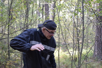 пожилой человек уклоняется от веток молодых деревьев © sashasandro