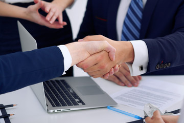 Business handshake at meeting or negotiation in the office, close-up. Partners are satisfied because signing contract or financial papers