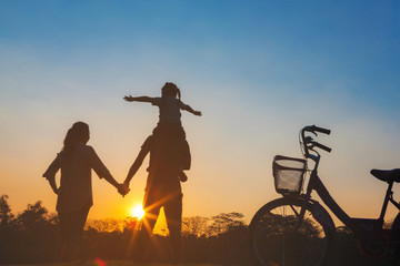 Obraz premium Happy family together, parents with their little child at sunset. Father raising baby up in the airing.