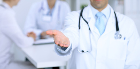 Male medicine doctor offering helping hand  for  handshake. Partnership and trust concept. 