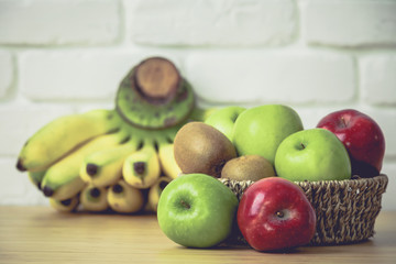Fresh fruits in a basket on a wooden background .