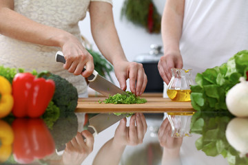 Close-up of  human hands  cooking in a kitchen. Friends having fun while preparing fresh salad. Vegetarian, healthy meal and friendship concept