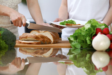 Close-up of human hands slicing bread in a kitchen. Friends having fun while cooking in the kitchen. Chef cook represent culinary masterclass