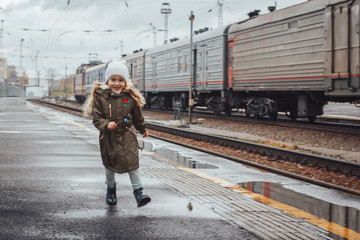 Small cute girl on railway station in an autumn
