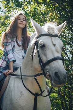 Girl teenager and white horse in a park in a summer