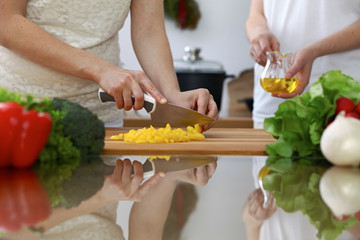 Close-up of  human hands  cooking in a kitchen. Friends having fun while preparing fresh salad. Vegetarian, healthy meal and friendship concept