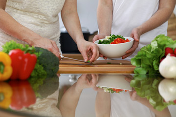 Close-up of  human hands  cooking in a kitchen. Friends having fun while preparing fresh salad. Vegetarian, healthy meal and friendship concept