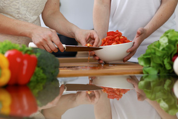 Close-up of  human hands  cooking in a kitchen. Friends having fun while preparing fresh salad. Vegetarian, healthy meal and friendship concept