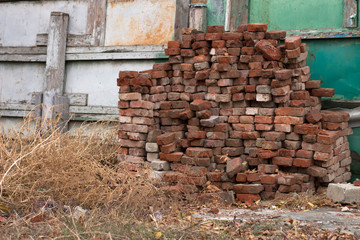 dry grass and old bricks stacked up against the fence