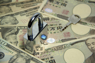 Key to Success of business and finance, The lock and key on the pile of US and Japanese banknotes.