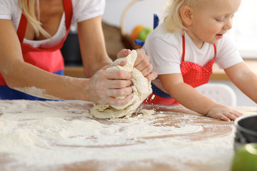 Mother and her cute daughter hands prepares the dough on wooden table. Homemade pastry for bread or pizza. Bakery background