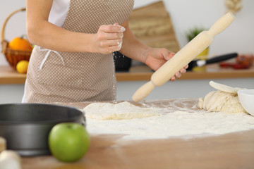 Female hands making dough for pizza or bread while using rolling pin. Baking concept