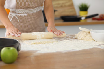 Female hands making dough for pizza or bread while using rolling pin. Baking concept